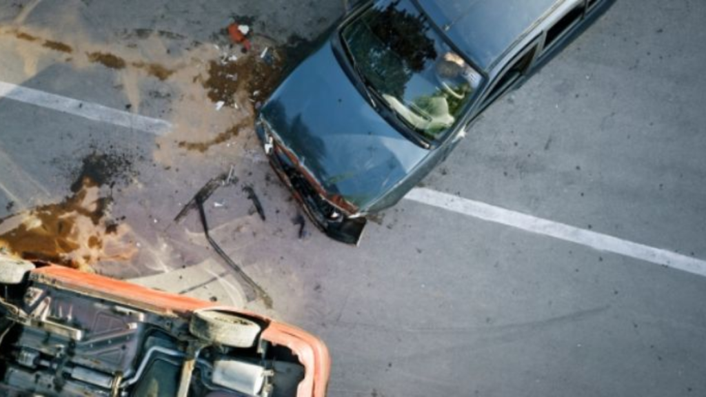 Top-down View of a Blue Sedan with Front-end Damage After a Collision Next to an Overturned Orange Car in a Parking Lot. | Nl Urbano